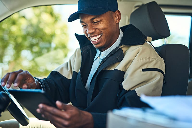 Shot of a courier using a digital tablet while sitting in a delivery van